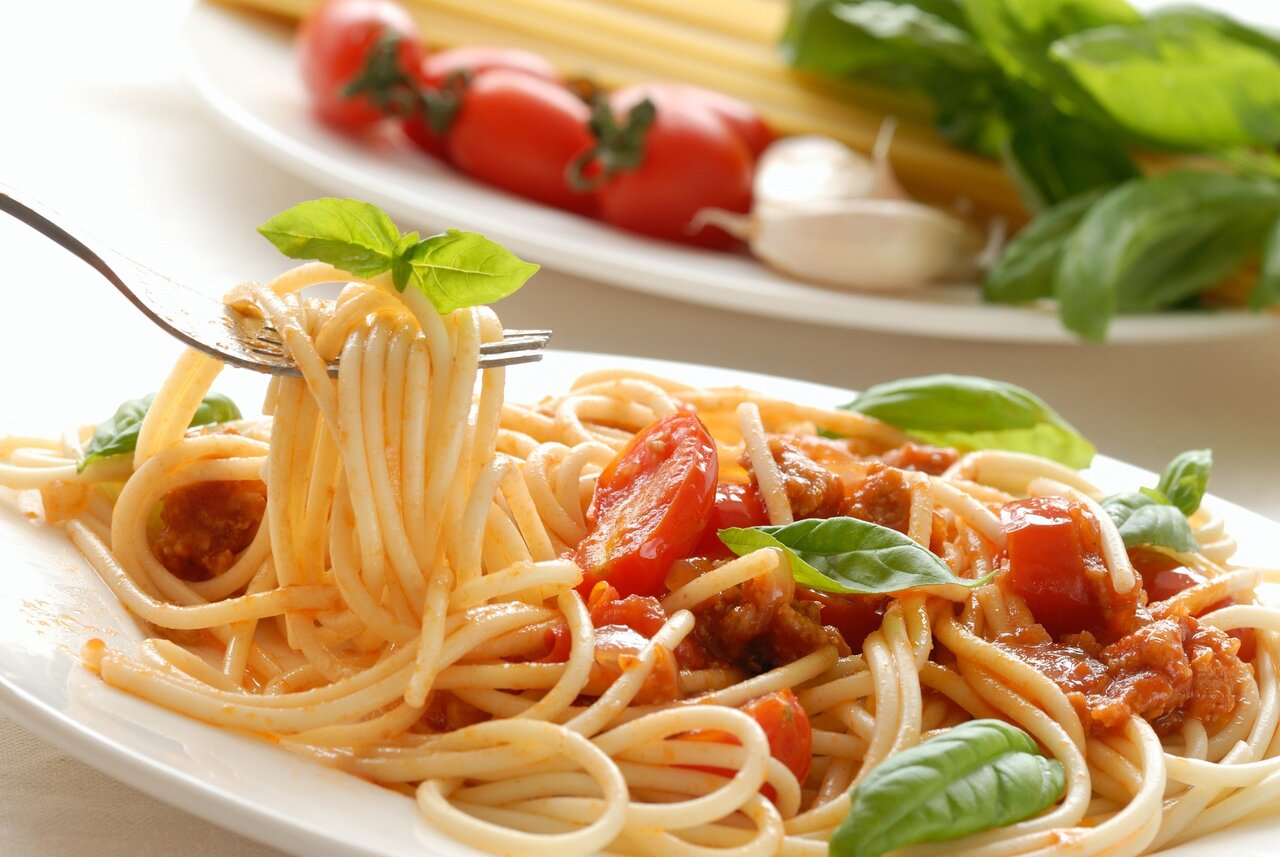 Ein Teller Spaghetti mit Tomatensoße, Basilikum und Knoblauch.